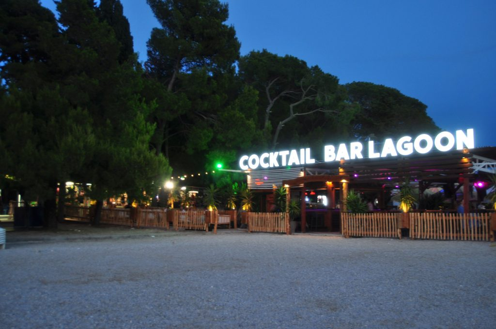 Cocktail Bar Lagoon o zmierzchu, z podświetlonym szyldem i tarasem