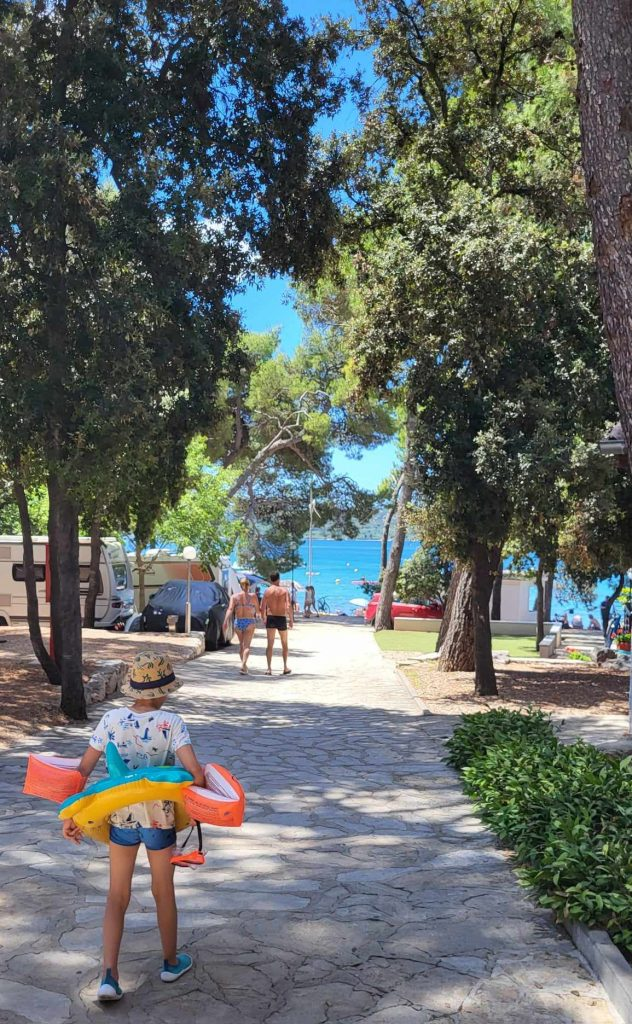 Zacieniona ścieżka przez Camping Park Soline prowadząca do plaży