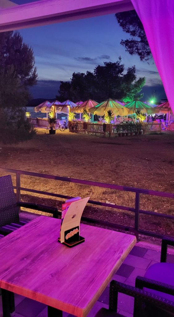 Wieczorem oświetlona restauracja z parasolami przy morzu w Biogradzie