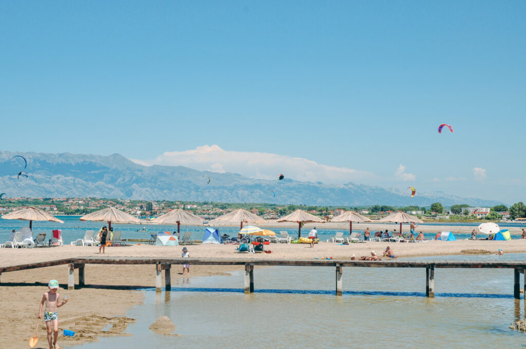 Piaszczysta plaża w okolicach Ninu z płytką wodą i górami Velebitu w tle